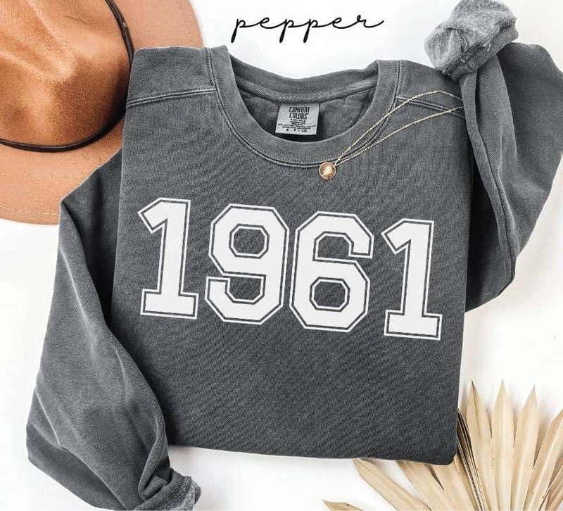 Gray (pepper) sweatshirt with '1961' printed on it, worn by a person, with a plain background.