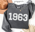 Gray (pepper) sweatshirt with '1963' printed on it, worn by a person, with a plain background.