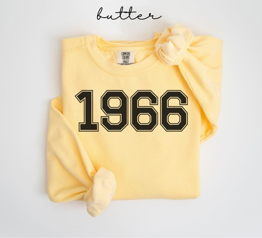 Yellow (butter) sweatshirt with '1966' printed on it, folded and displayed against a white background.
