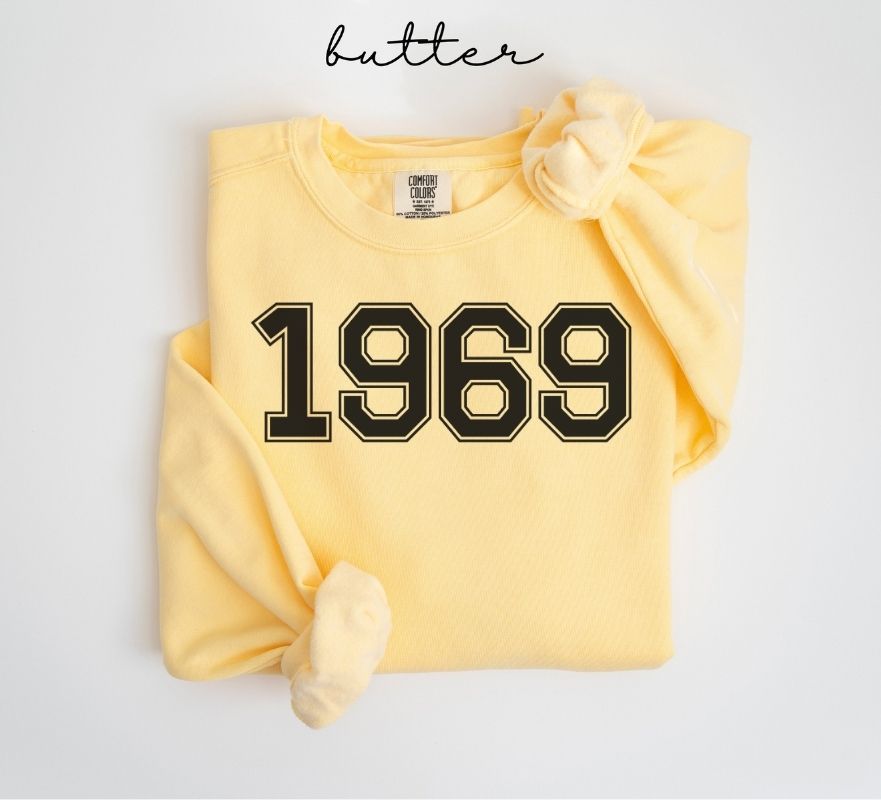 Yellow (butter) sweatshirt with '1969' printed on it, folded and displayed against a white background.