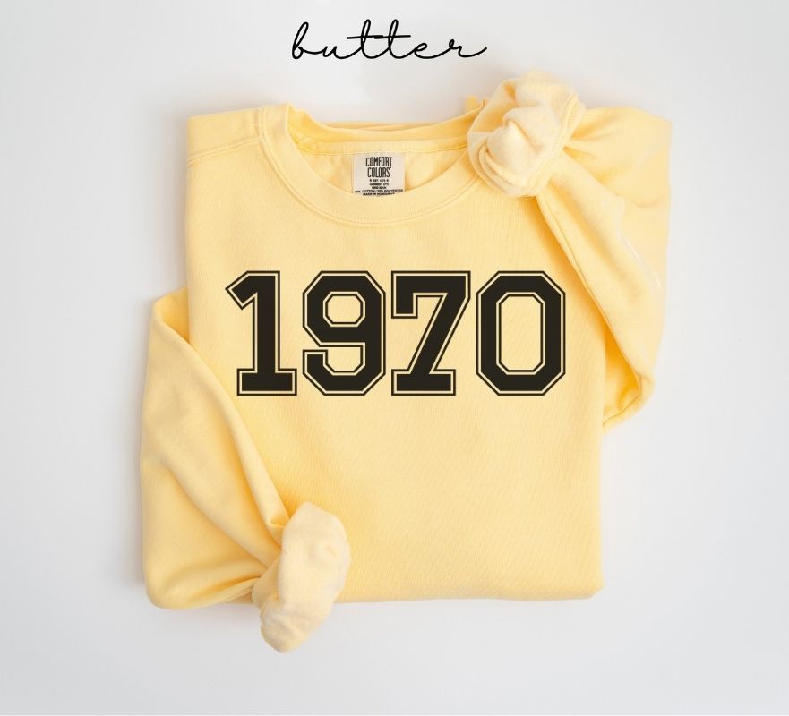 Yellow (butter) sweatshirt with '1970' printed on it, folded and displayed against a white background.