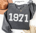 Gray (pepper) sweatshirt with '1971' printed on it, worn by a person, with a plain background.

