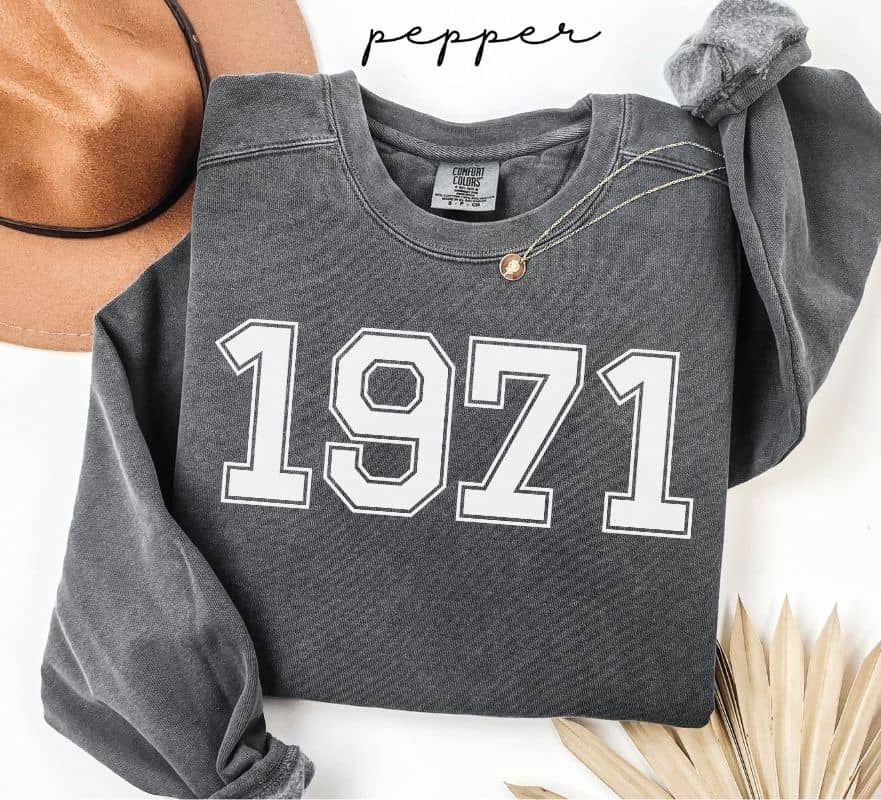 Gray (pepper) sweatshirt with '1971' printed on it, worn by a person, with a plain background.
