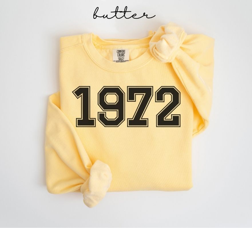 Yellow (butter) sweatshirt with '1972' printed on it, folded and displayed against a white background.