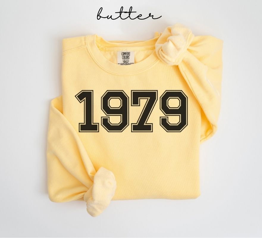 Yellow (butter) sweatshirt with '1979' printed on it, folded and displayed against a white background.