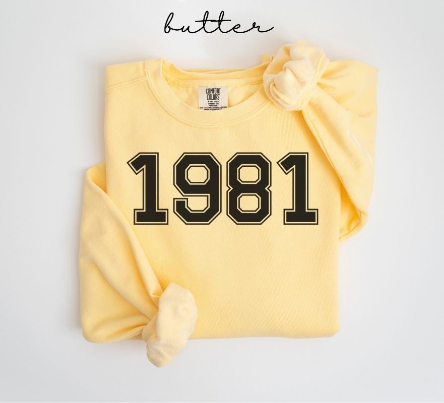 Yellow (butter) sweatshirt with '1981' printed on it, folded and displayed against a white background.