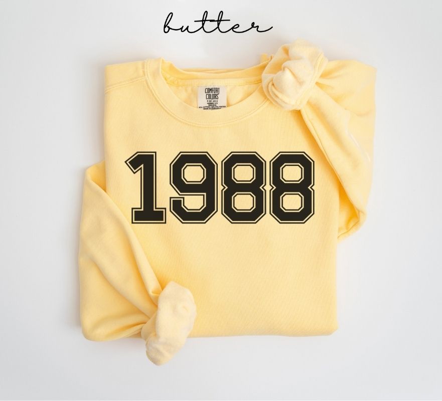 Yellow (butter) sweatshirt with '1988' printed on it, folded and displayed against a white background.
