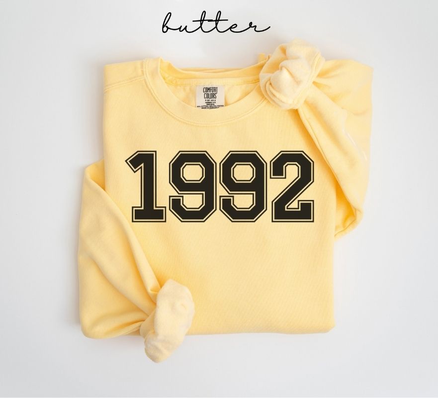 Yellow (butter) sweatshirt with '1992' printed on it, folded and displayed against a white background.