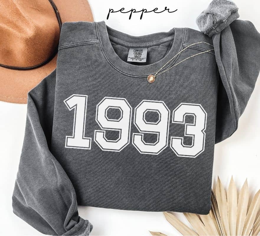 Gray (pepper) sweatshirt with '1993' printed on it, worn by a person, with a plain background.
