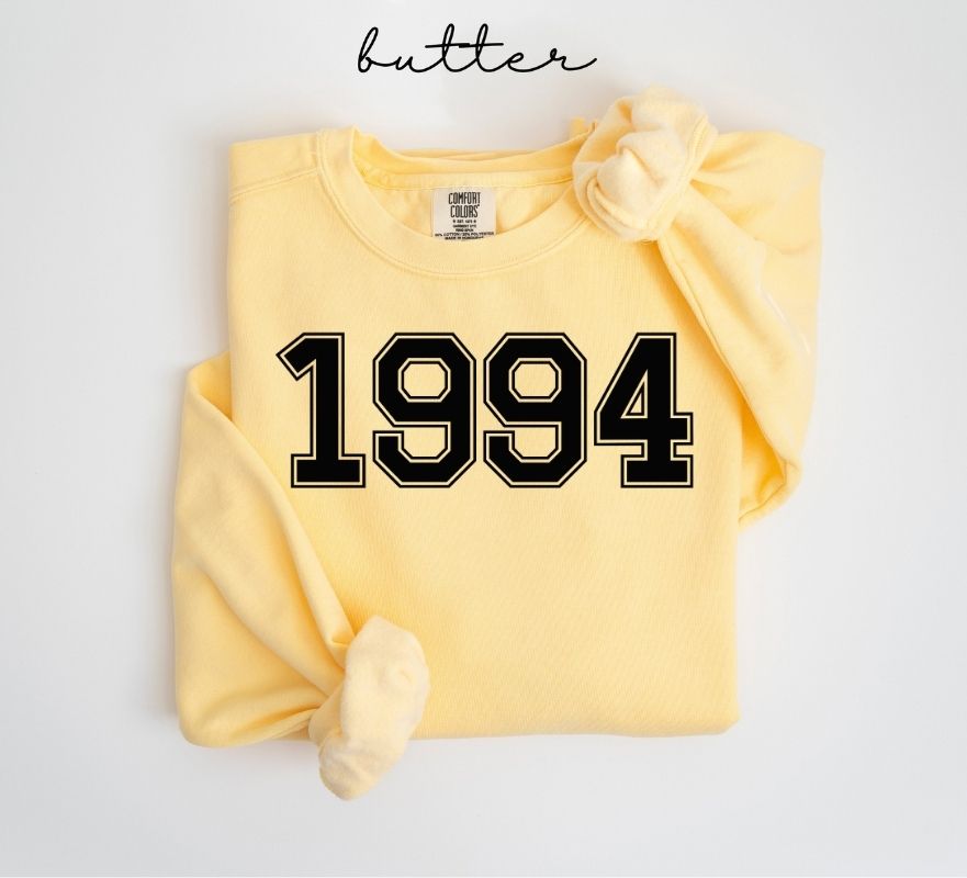 Yellow (butter) sweatshirt with '1994' printed on it, folded and displayed against a white background.
