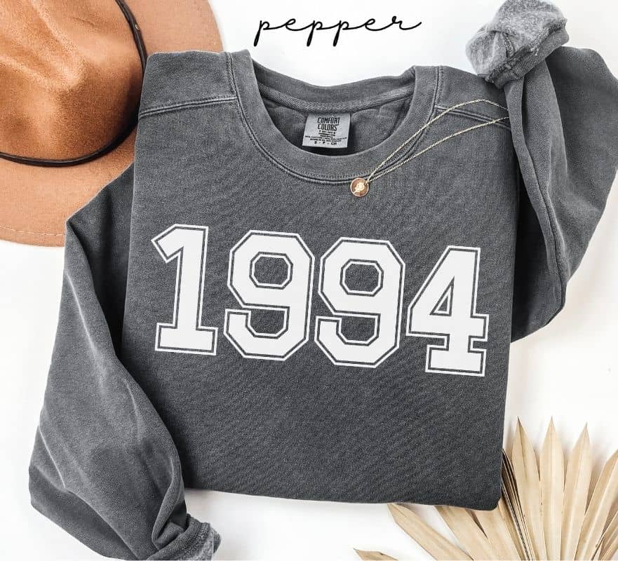 Gray (pepper) sweatshirt with '1994' printed on it, worn by a person, with a plain background.
