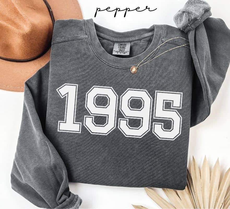 Gray (pepper) sweatshirt with '1995' printed on it, worn by a person, with a plain background.
