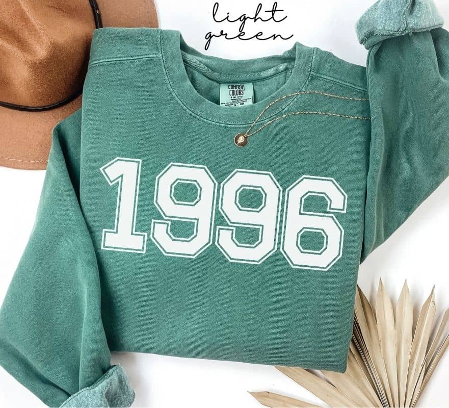 Light green sweatshirt with '1996' printed on it, displayed on a white background.

