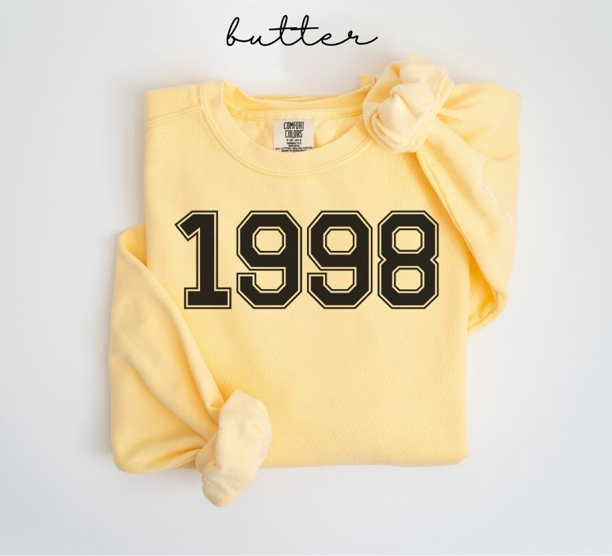 Yellow (butter) sweatshirt with '1998' printed on it, folded and displayed against a white background.
