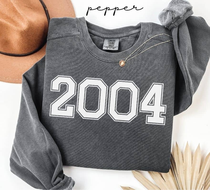 Gray (pepper) sweatshirt with '2004' printed on it, worn by a person, with a plain background.
