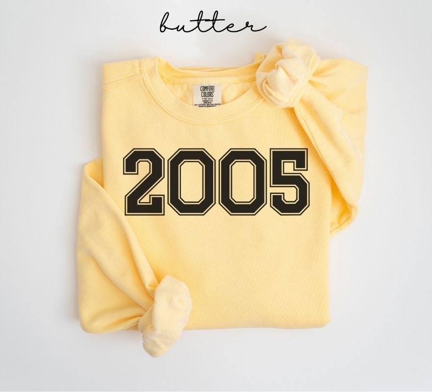 Yellow (butter) sweatshirt with '2005' printed on it, folded and displayed against a white background.