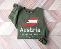 Military green sweatshirt with Austria map design on a wooden floor.