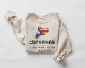 A beige (sand) sweatshirt featuring a Barcelona design on a white background.background
