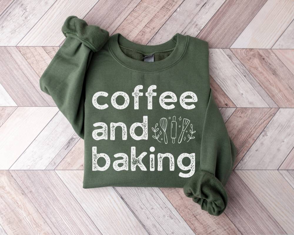 Military green sweatshirt with 'coffee and baking' text on a wooden floor