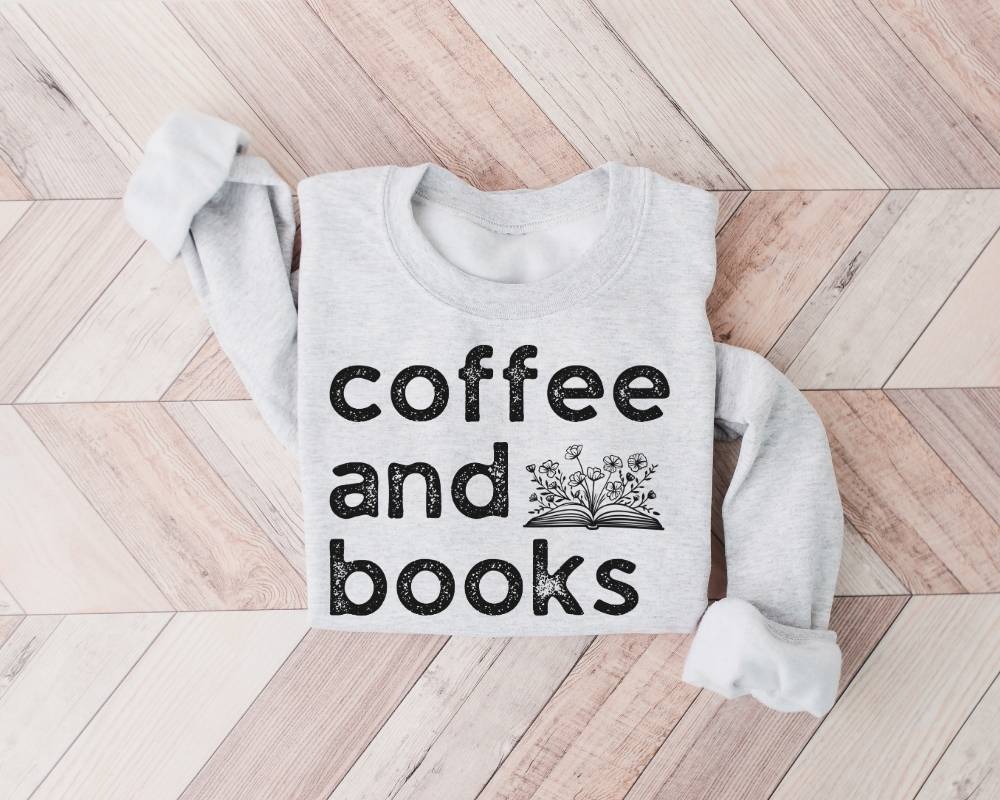 White (ash) sweatshirt with 'coffee and books' text on a wooden floor
