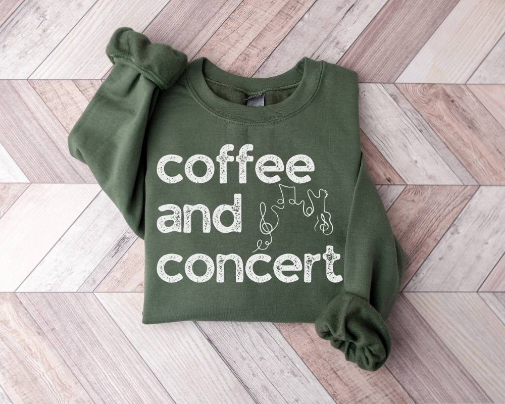 Military green sweatshirt with 'coffee and concert' text on a wooden floor