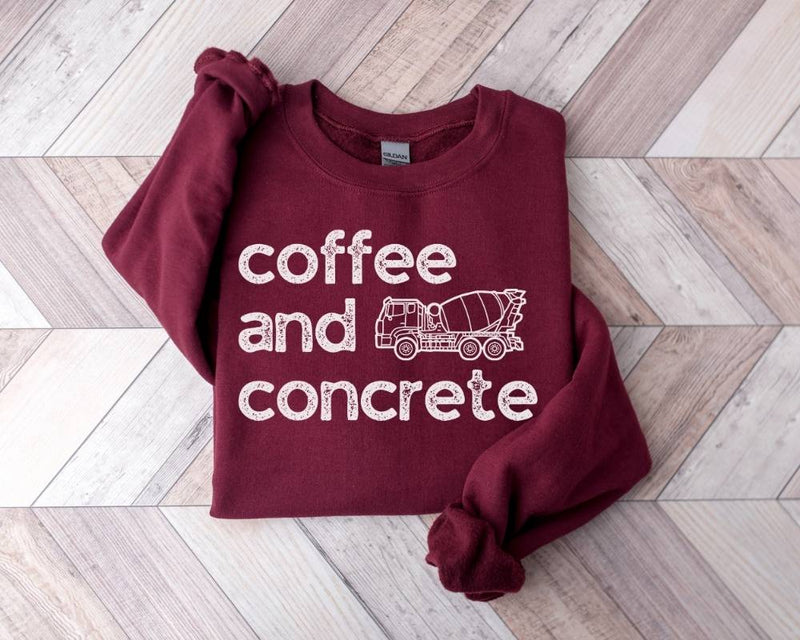 Maroon sweatshirt with 'coffee and concrete' and a cement mixer graphic on a wooden floor.