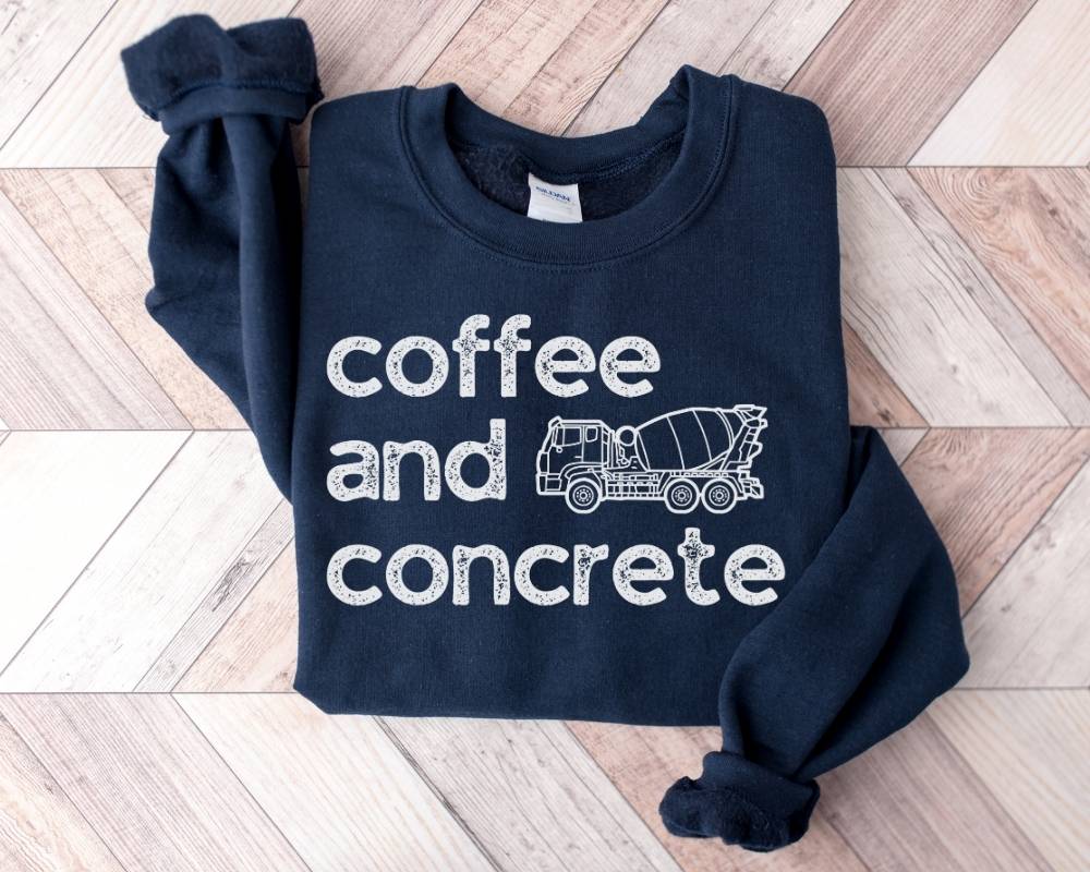 Navy blue sweatshirt with 'coffee and concrete' and a cement mixer graphic on a wooden floor.