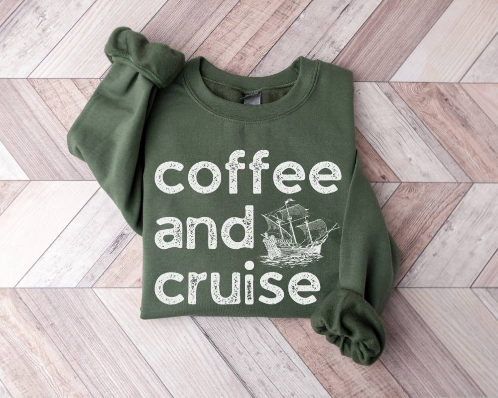 Military green sweatshirt with 'coffee and cruise' text and ship graphic on a wooden floor.