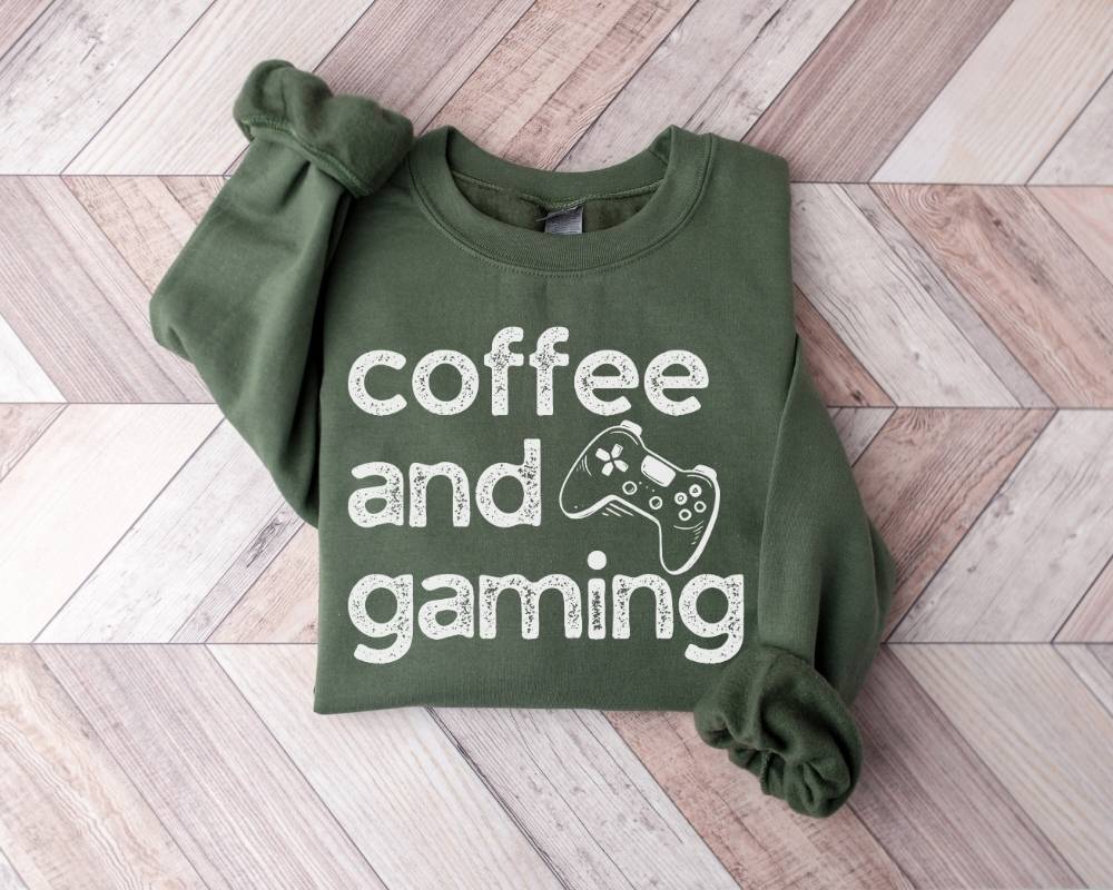 Military green sweatshirt with 'coffee and gaming' text on a wooden floor