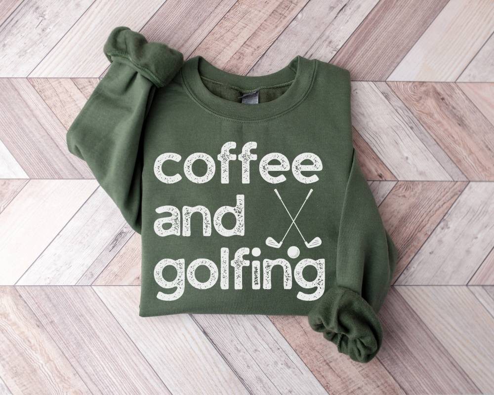 Military green sweatshirt with 'coffee and golfing' text on a wooden floor