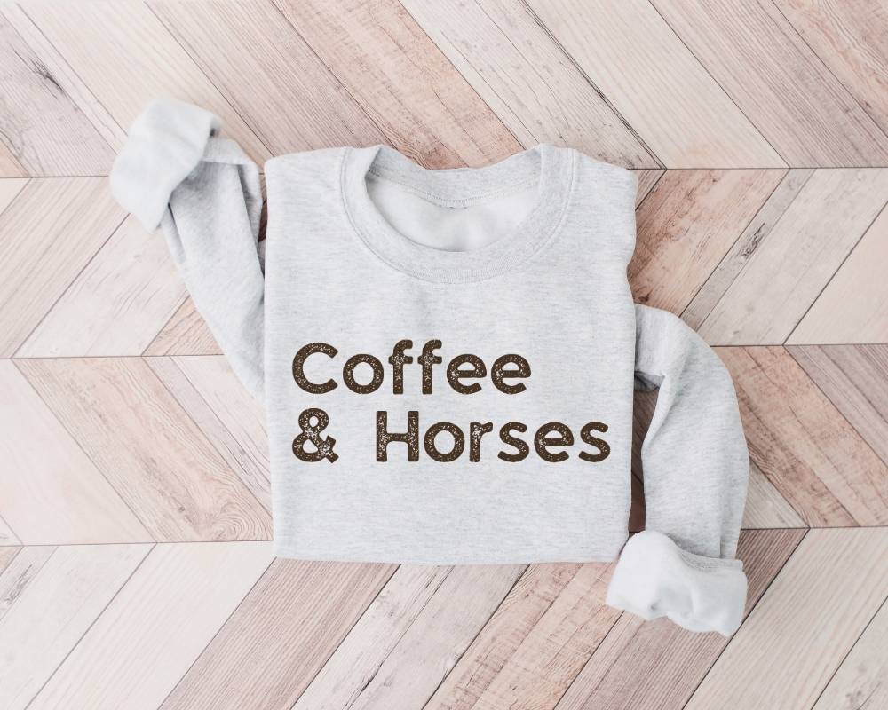 White (ash) sweatshirt with 'Coffee & Horses' text on a wooden floor
