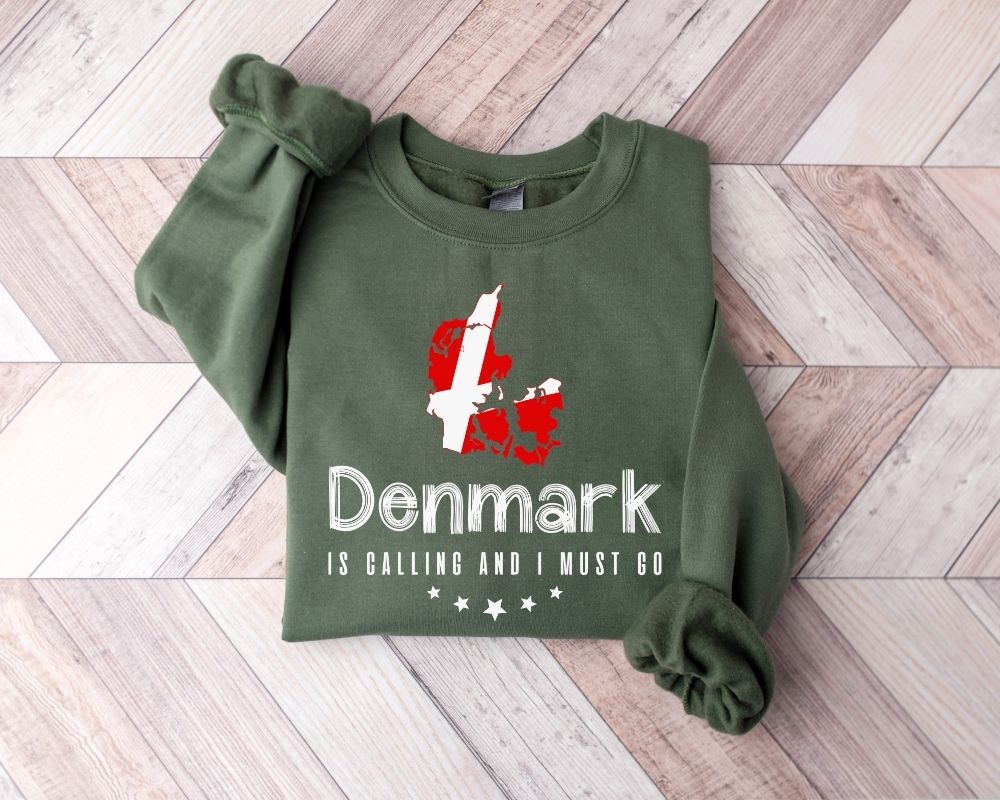 Military green sweatshirt featuring the text 'Denmark is calling, and I must go' with a flag design on a wooden floor.