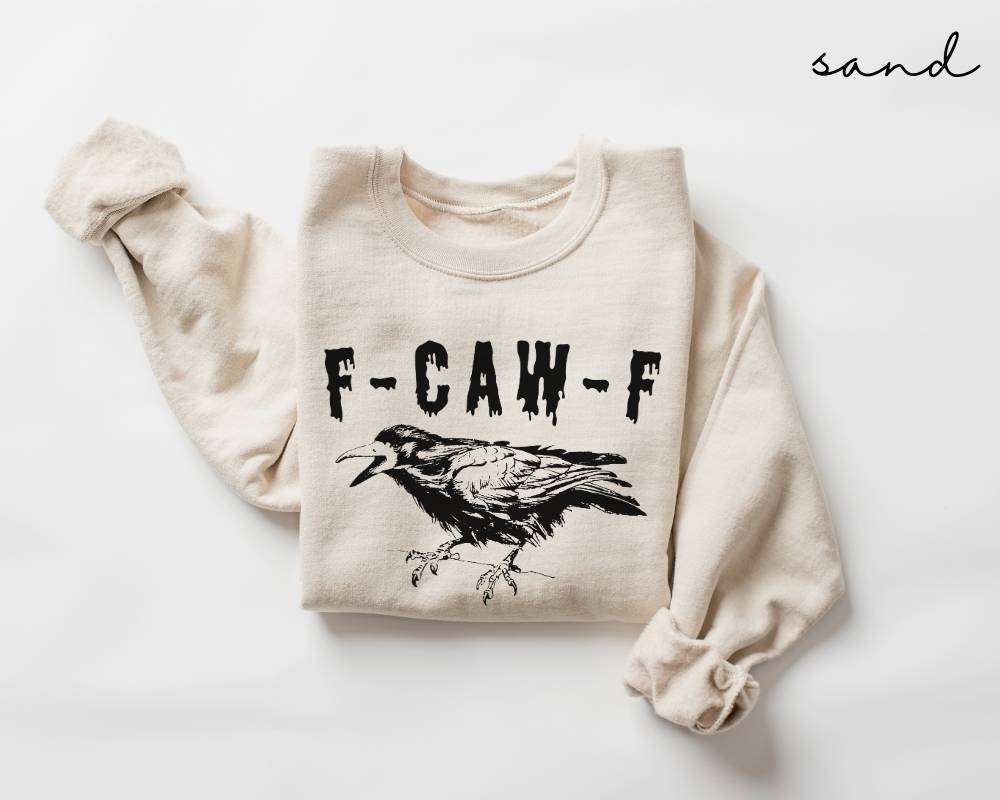 Beige (sand) sweatshirt with a black graphic design of a crow and text on a white background