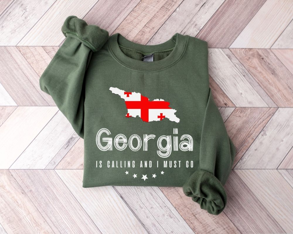 Military green sweatshirt with Georgia map and text on a wooden floor