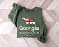 Military green sweatshirt with Georgia map and text on a wooden floor