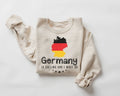 A beige (sand) sweatshirt featuring a design of the German flag along with text on a white background.