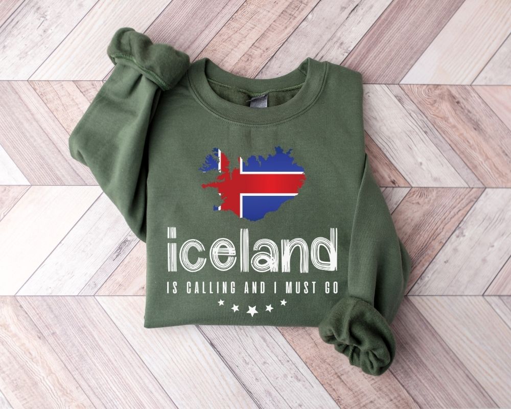 Military green sweatshirt with Icelandic flag design and text on a wooden floor