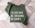 Military green sweatshirt with text 'I'd rather be arguing in court' on a wooden floor.