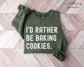 Military green sweatshirt with 'I'd rather be baking cookies' text on a wooden floor.