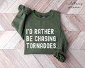 Military green sweatshirt with 'I'd Rather Be Chasing Tornadoes' text on a wooden floor.