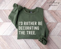 Military green sweatshirt with text 'I'd rather be decorating the tree' on a wooden floor.