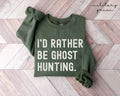 Military green sweatshirt with 'I'd Rather Be Ghost Hunting' text on a wooden floor.