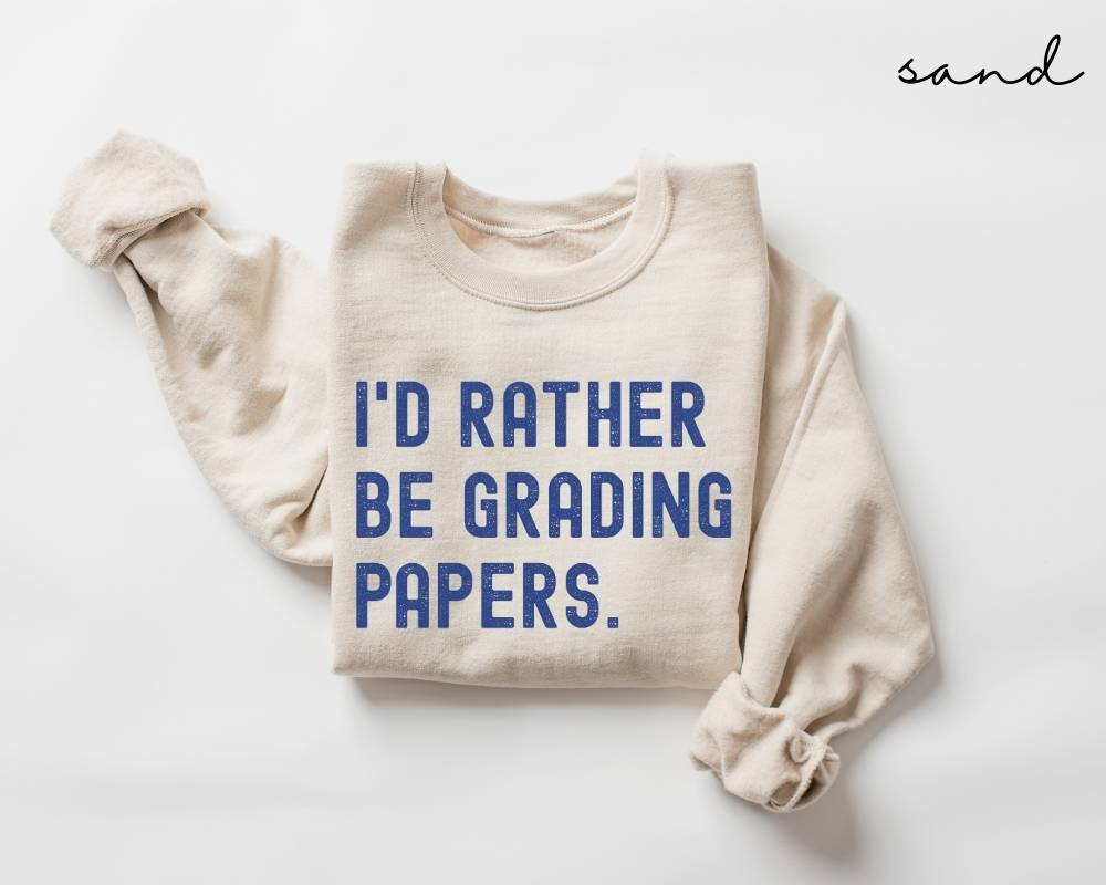 Beige (sand) sweatshirt with blue text 'I'd rather be grading papers' on a white background