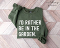 Military green sweatshirt with 'I'd rather be in the garden' text on a wooden floor.