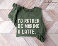 Military green sweatshirt with 'I'd rather be making a latte' text on a wooden floor.
