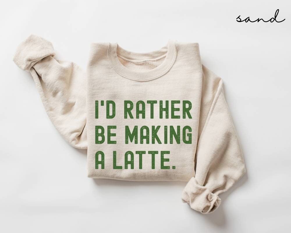Beige (sand) sweatshirt with green text 'I'd rather be making a latte' on a white background