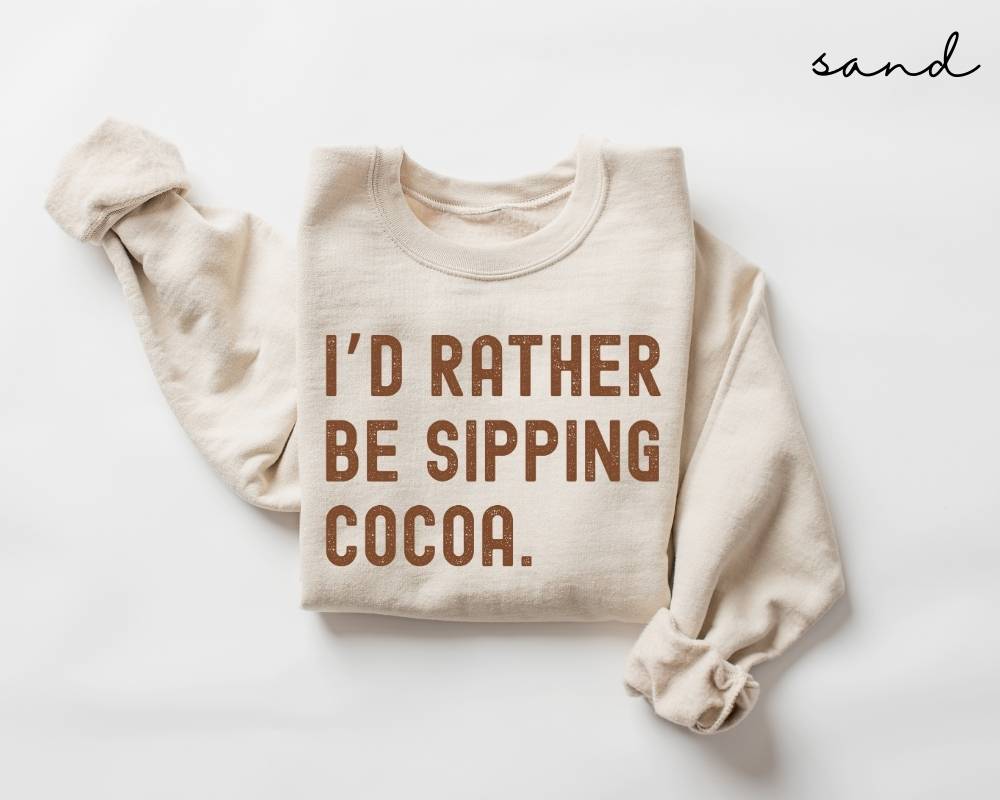 Beige (sand) sweatshirt with 'I'd Rather Be Sipping Cocoa' text on a white background