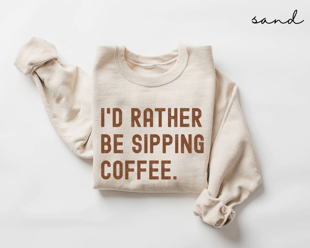 Beige (sand) sweatshirt with 'I'd Rather Be Sipping Coffee' text on a white background