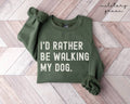 Military green sweatshirt with 'I'd Rather Be Walking My Dog' text on a wooden floor.