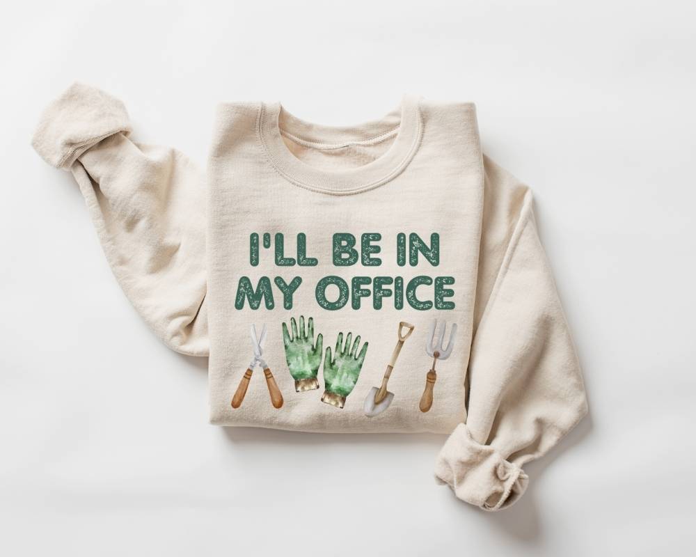 Beige (sand) sweatshirt with 'I'll be in my office' text and gardening tools on a white background
